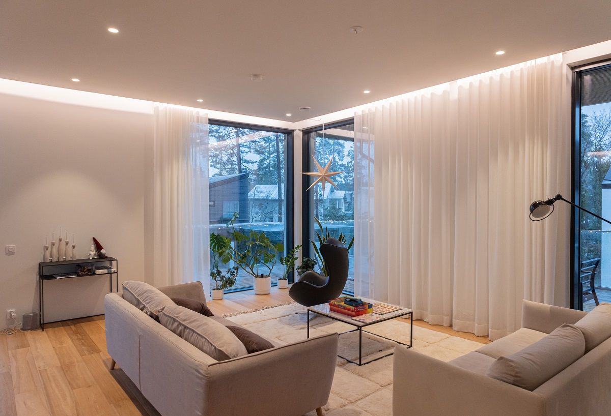 Gli elementi dell'illuminazione del soggiorno sono strisce LED indirette, spot a incasso e lampade da terra.